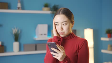 Asian-woman-stressed,-scared-by-what-she-sees-on-phone-screen.